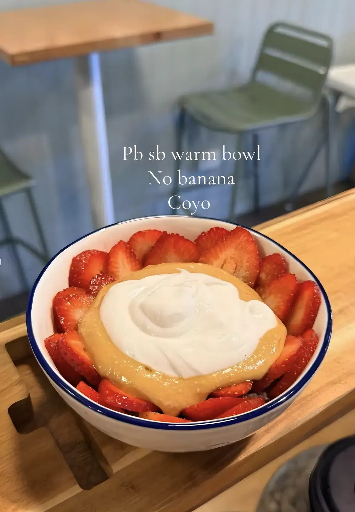 Warm bowl ringed with strawberries and topped with peanut butter and coconut yoghurt